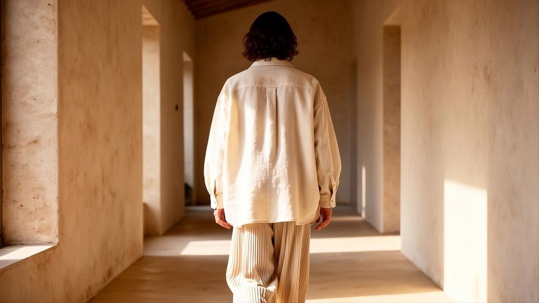 Person i monokrom beige outfit går genom en solbelyst korridor